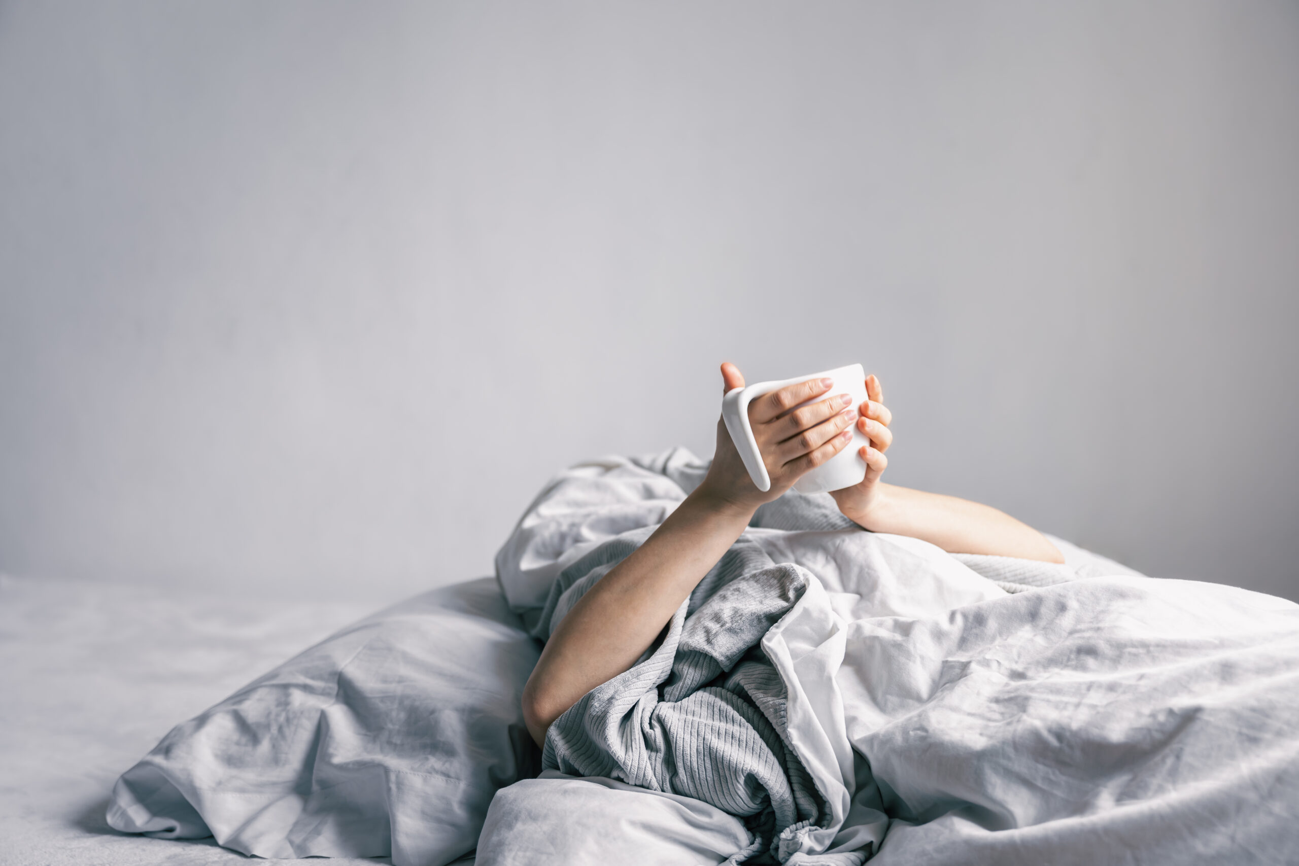 Womans Hand Holds Cup Coffee While Lying Bed Scaled